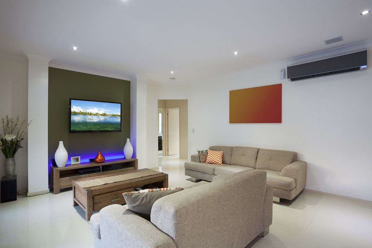 A living room with a couch and a television on the wall