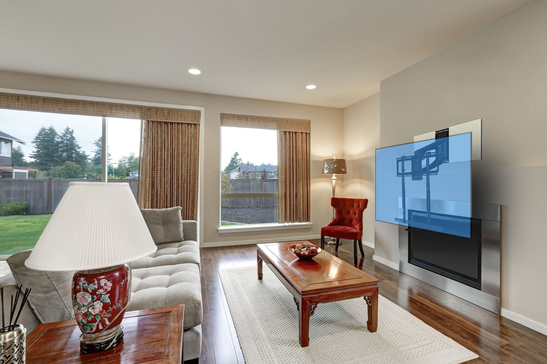 Living room with large windows, sofa, coffee table, and a TV mounted on the wall.