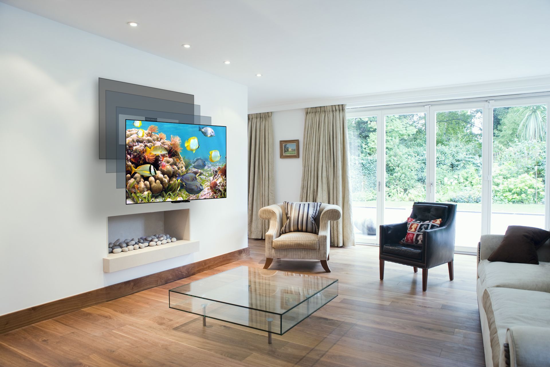 Living room with TV displaying an underwater scene. Features fireplace, two armchairs, glass table, and window overlooking foliage.