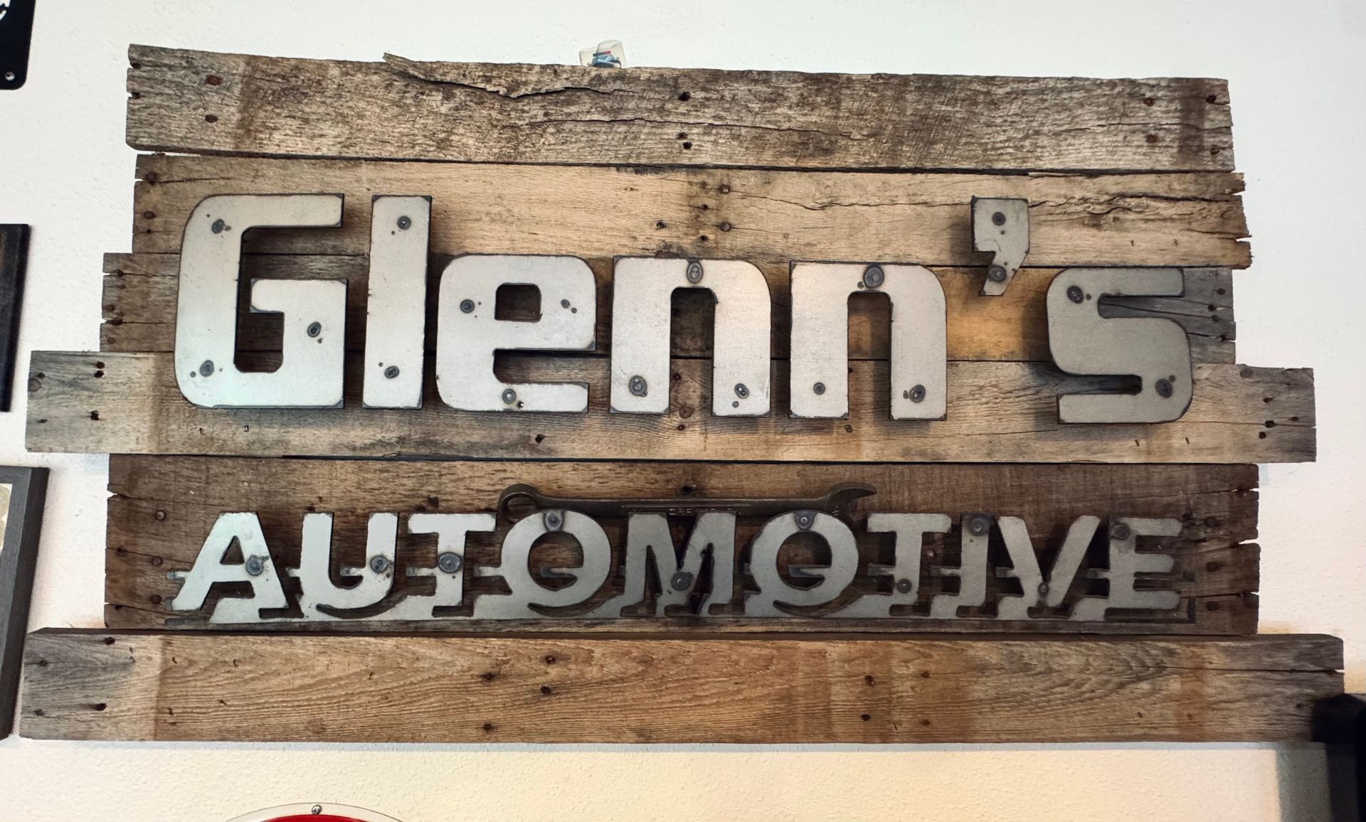 Glenn’s Automotive sign on a rustic wood wall, with white raised letters
