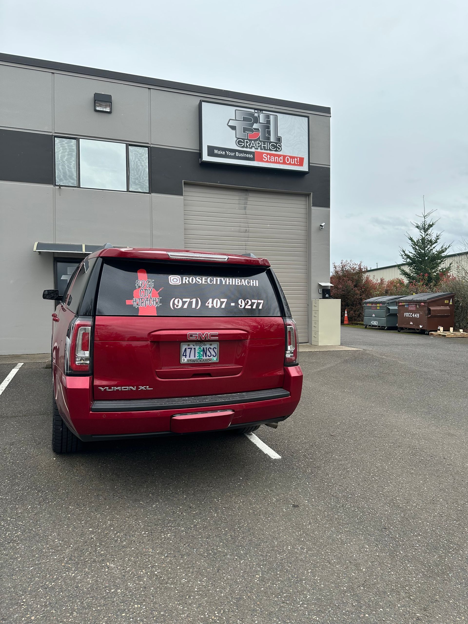 Red SUV parked outside a business building. Sign above the door. Cloudy day.