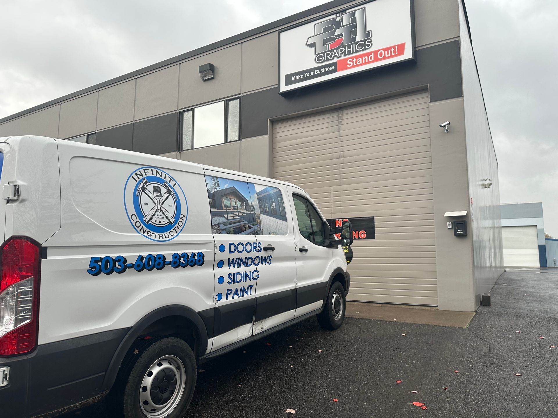 White van with company logo in front of a building with a closed garage door.