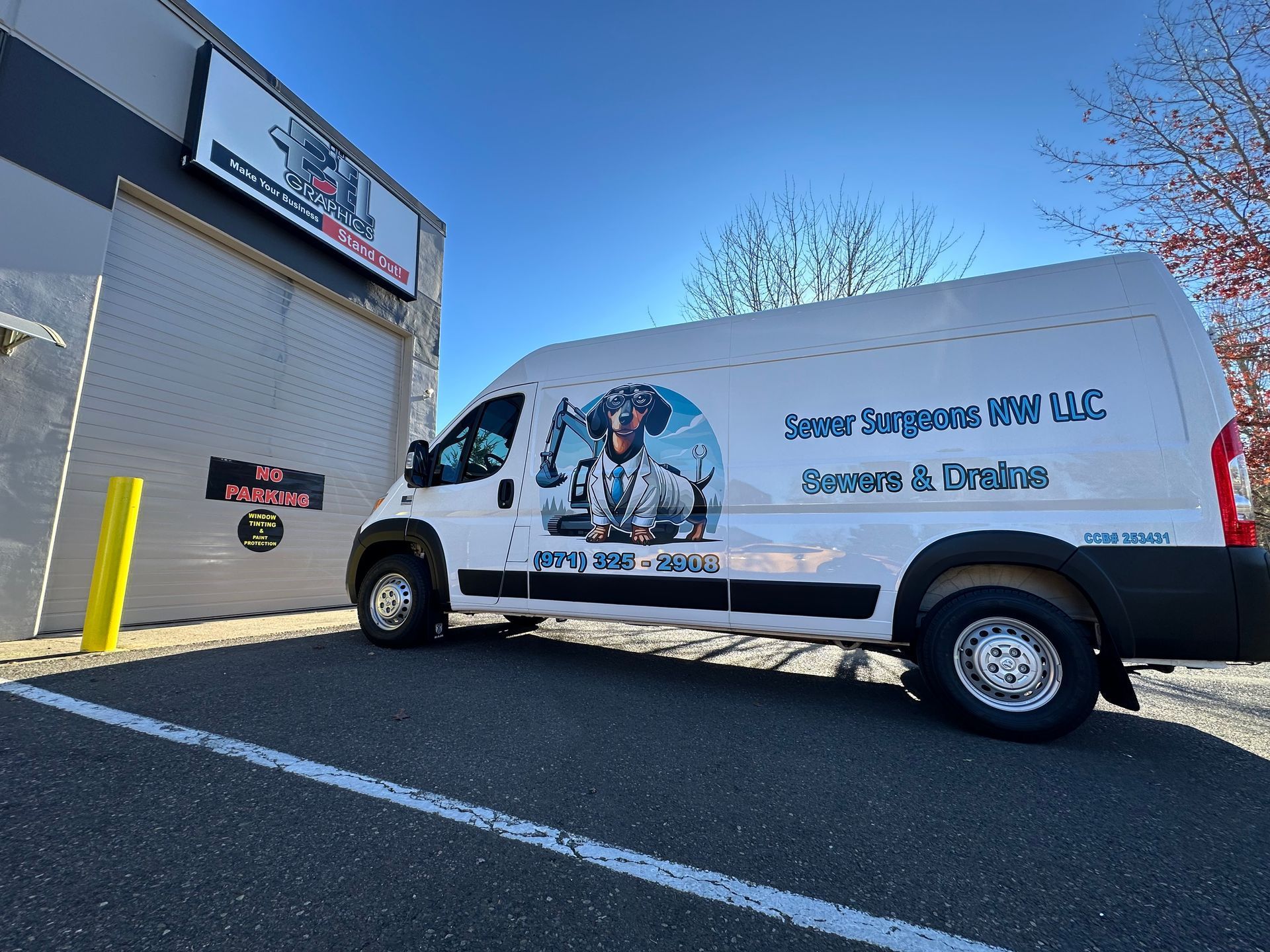 White van with company logo parked outside a building on a sunny day.
