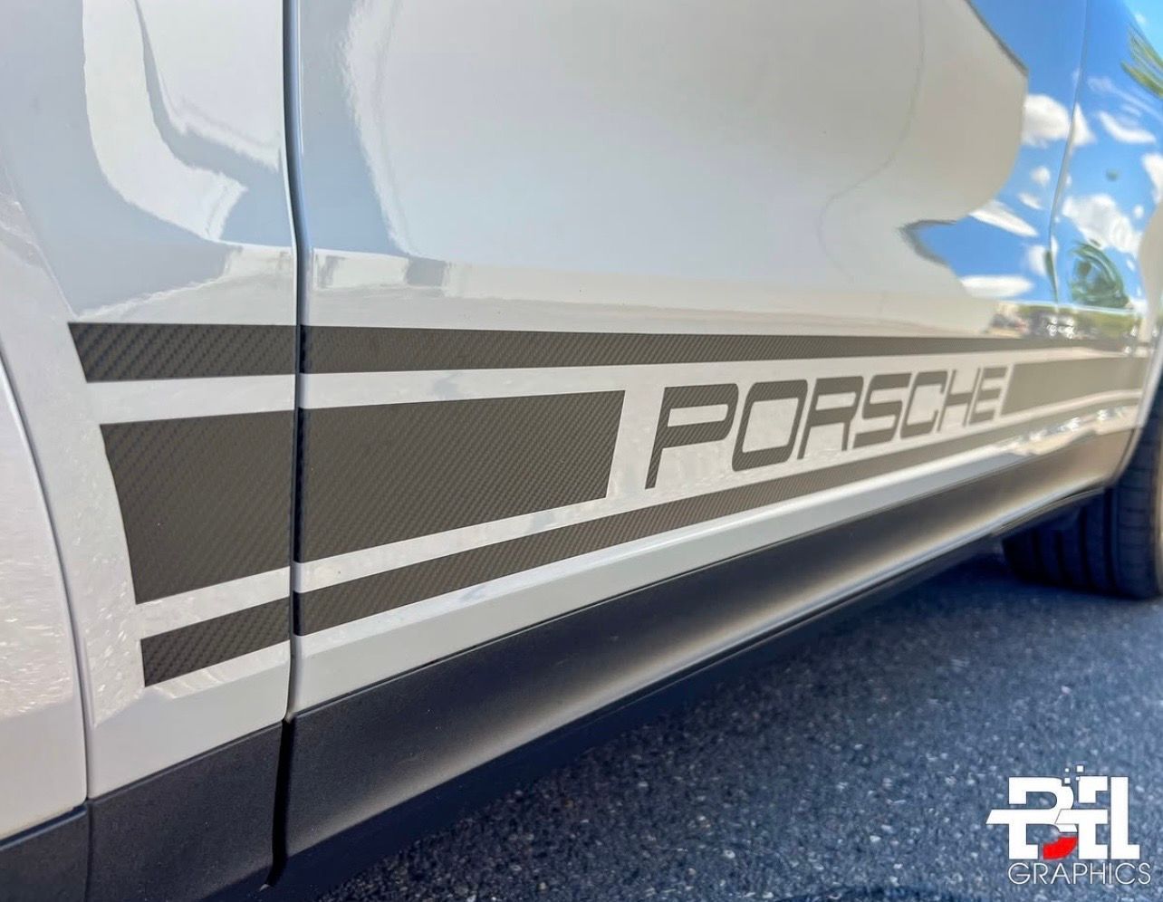 Close-up of a white Porsche with a black side stripe featuring the word 