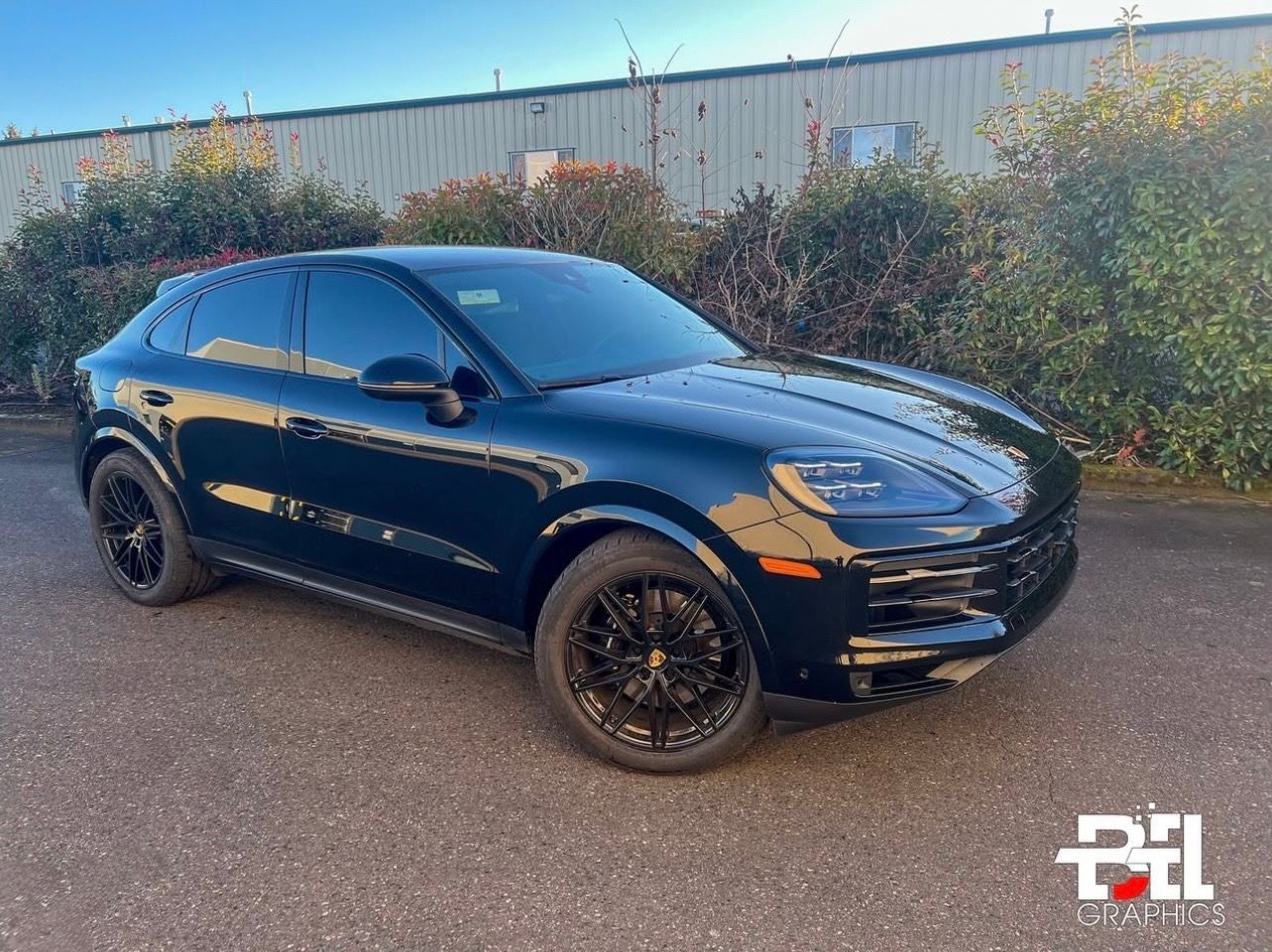 Black Porsche SUV parked outdoors with tinted windows and black rims.