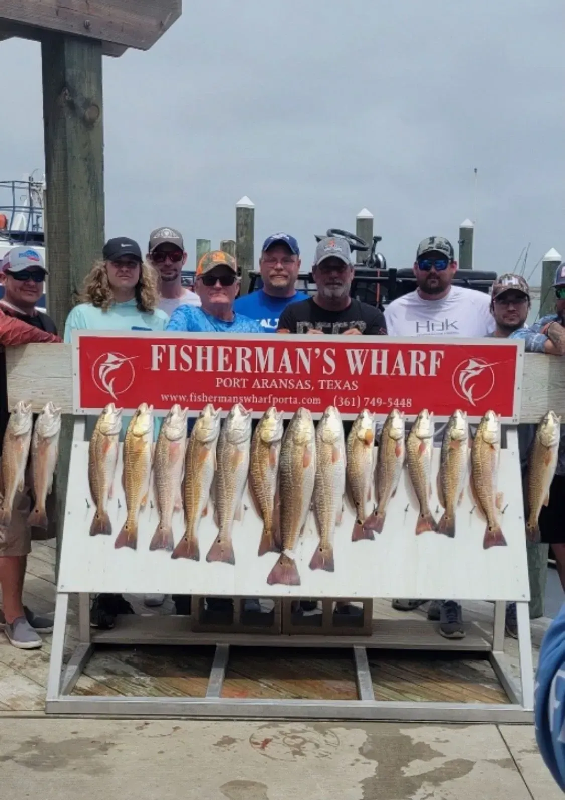 Group of people at Fisherman's Wharf, Port Aransas, Texas, displaying caught redfish.
