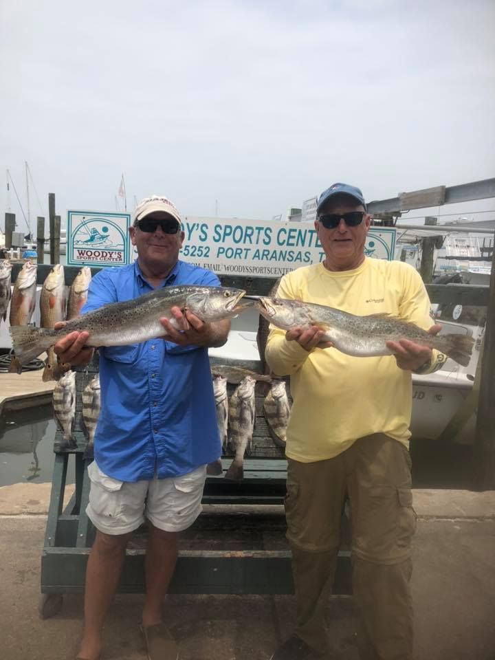 Two men holding speckled trout they caught in Port Aransas, Texas.