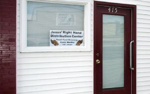 A white building with a red door and a sign