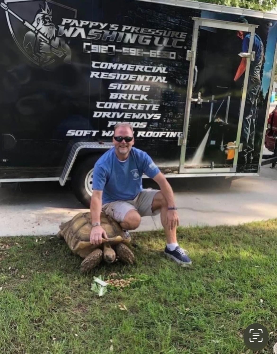 A man is sitting on a turtle in front of a trailer.