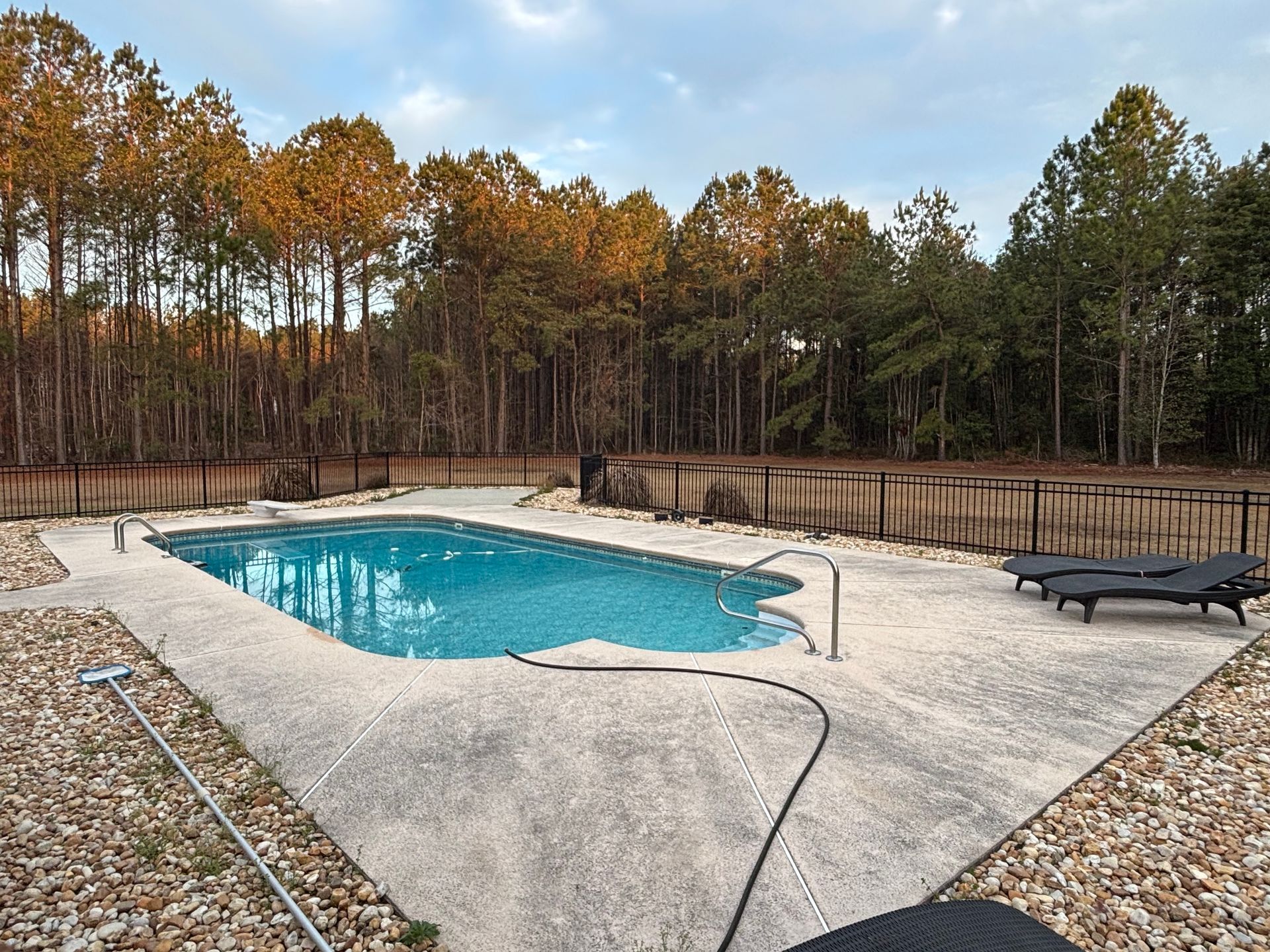 A large swimming pool is surrounded by rocks and trees