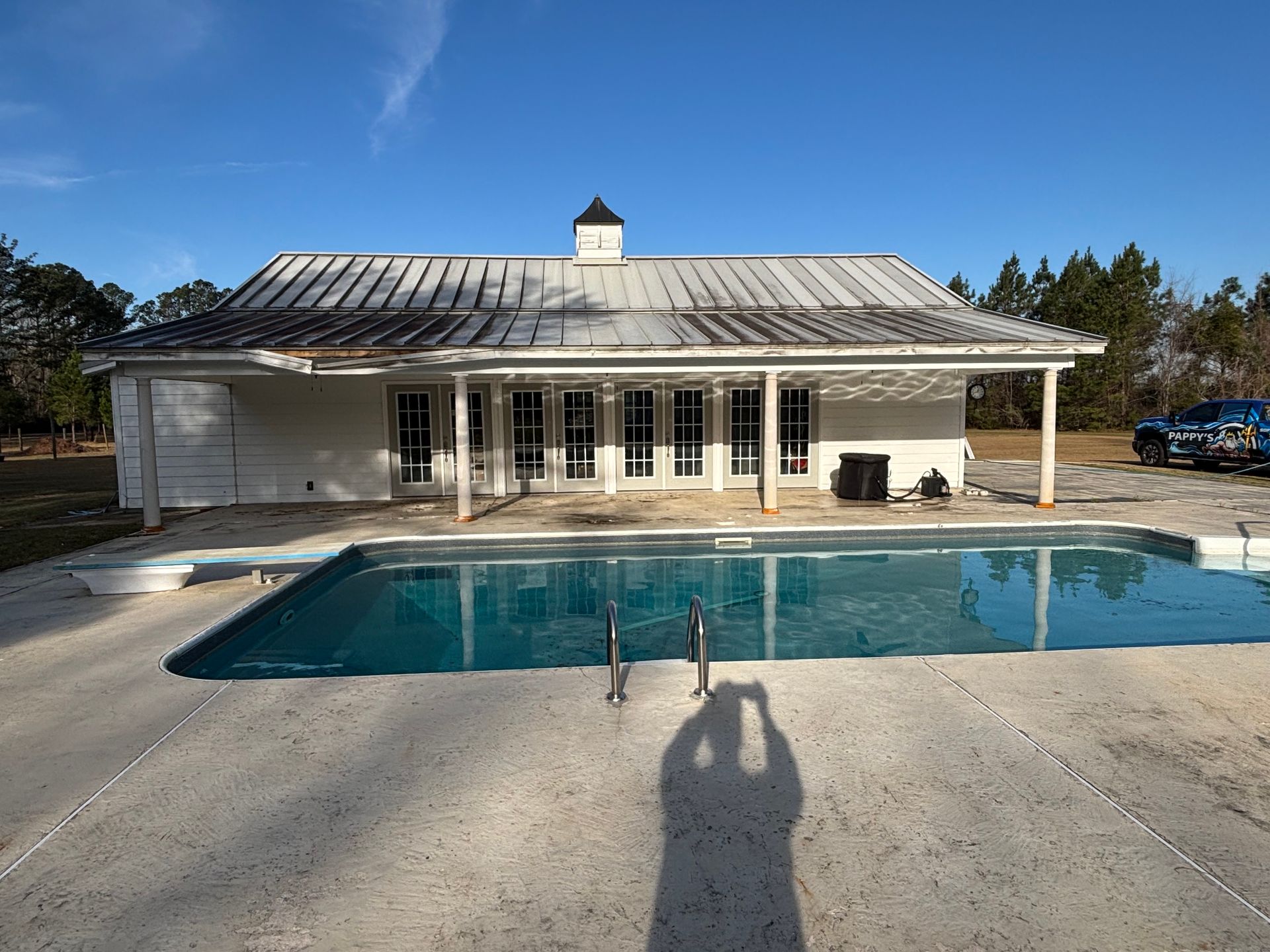 A white house with a large swimming pool in front of it