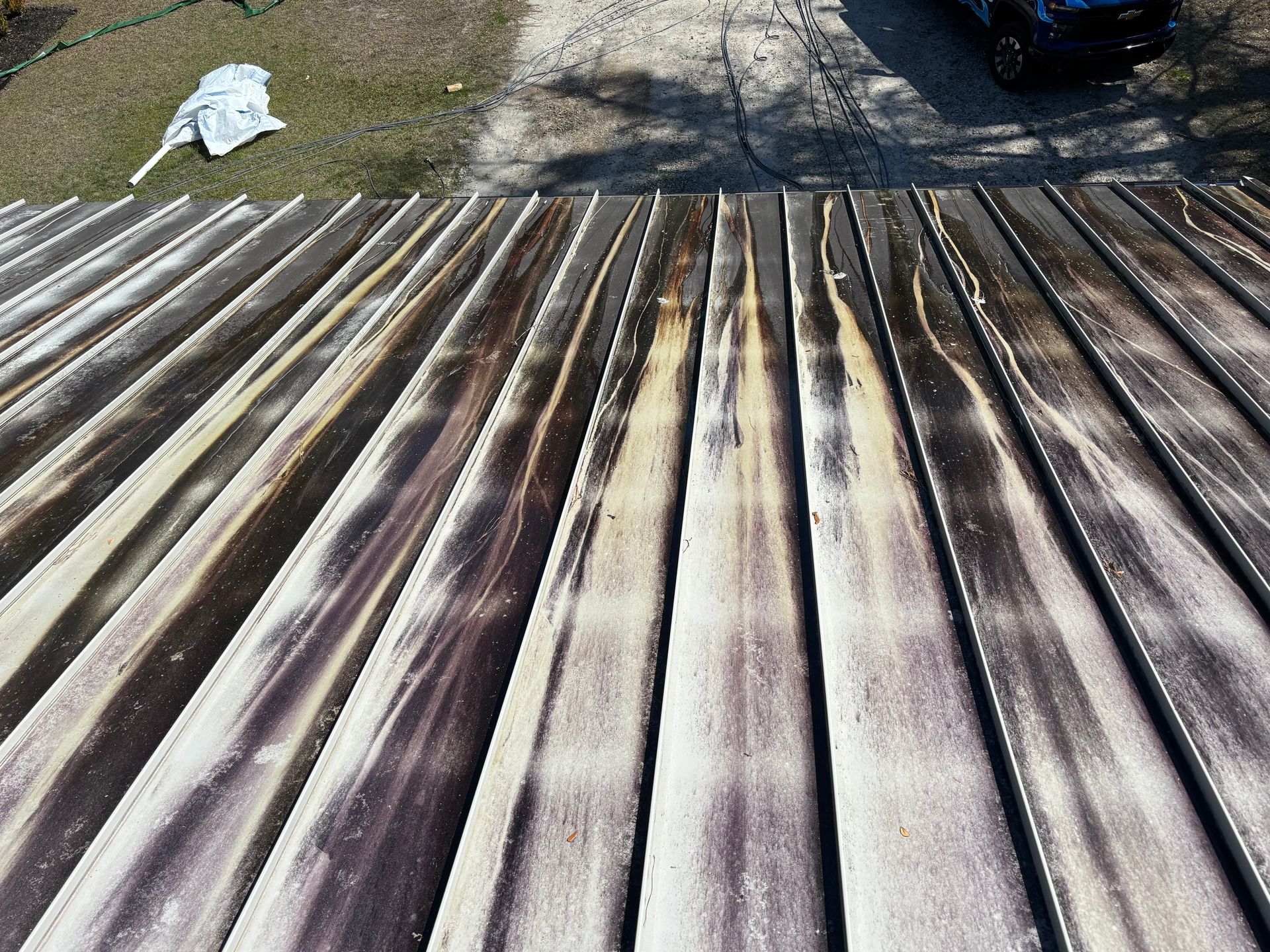 A close-up of a wooden deck with a car parked in the background