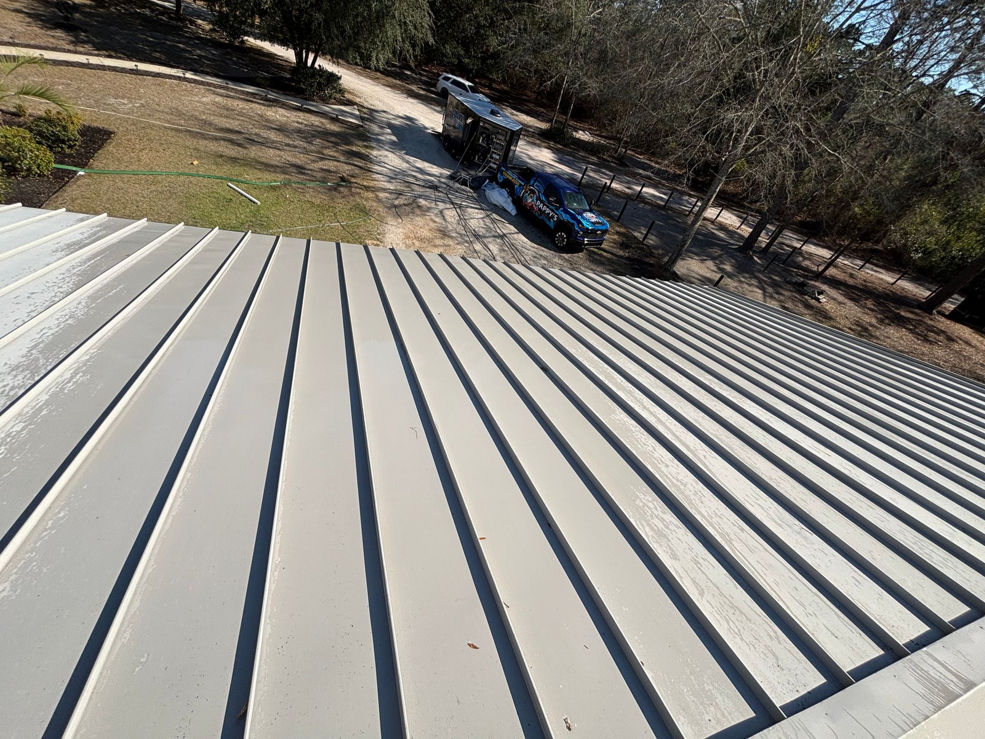 An aerial view of a metal roof with a car parked on the side of it