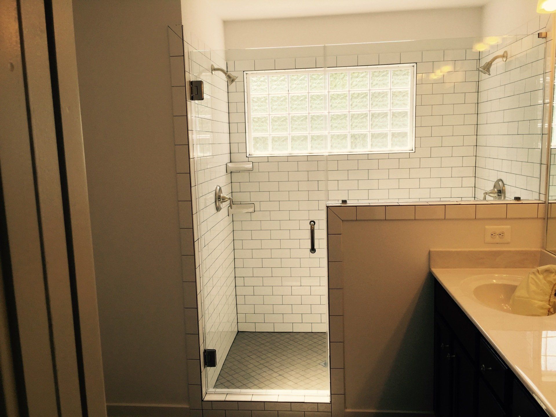 Bathroom with glass shower, white subway tile, and a glass block window.