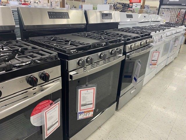 A row of stove tops and ovens are lined up in a store.
