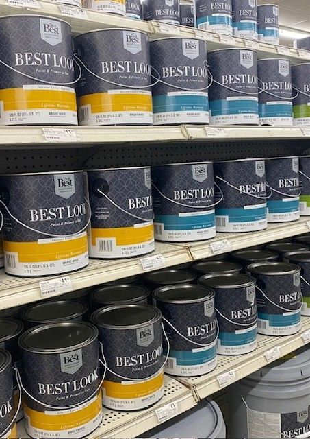 A shelf filled with buckets of paint in a store.