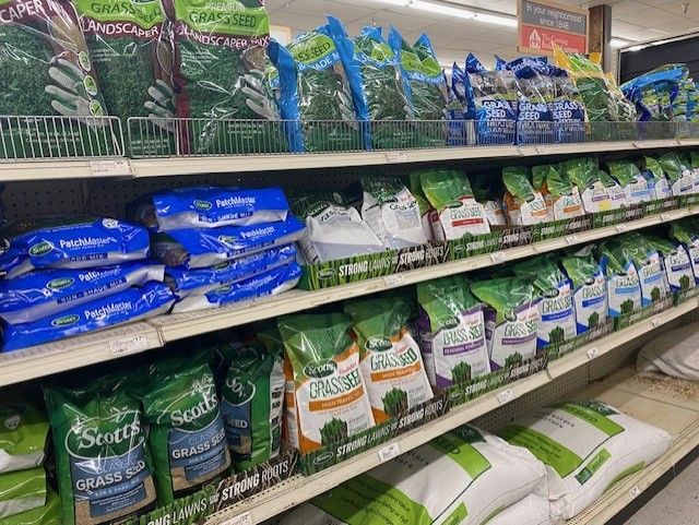 A shelf in a store filled with bags of grass.