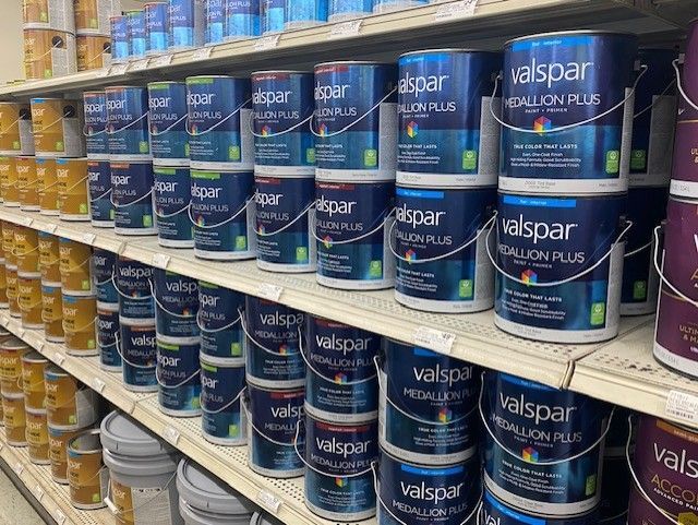 A store shelf filled with lots of cans of paint.