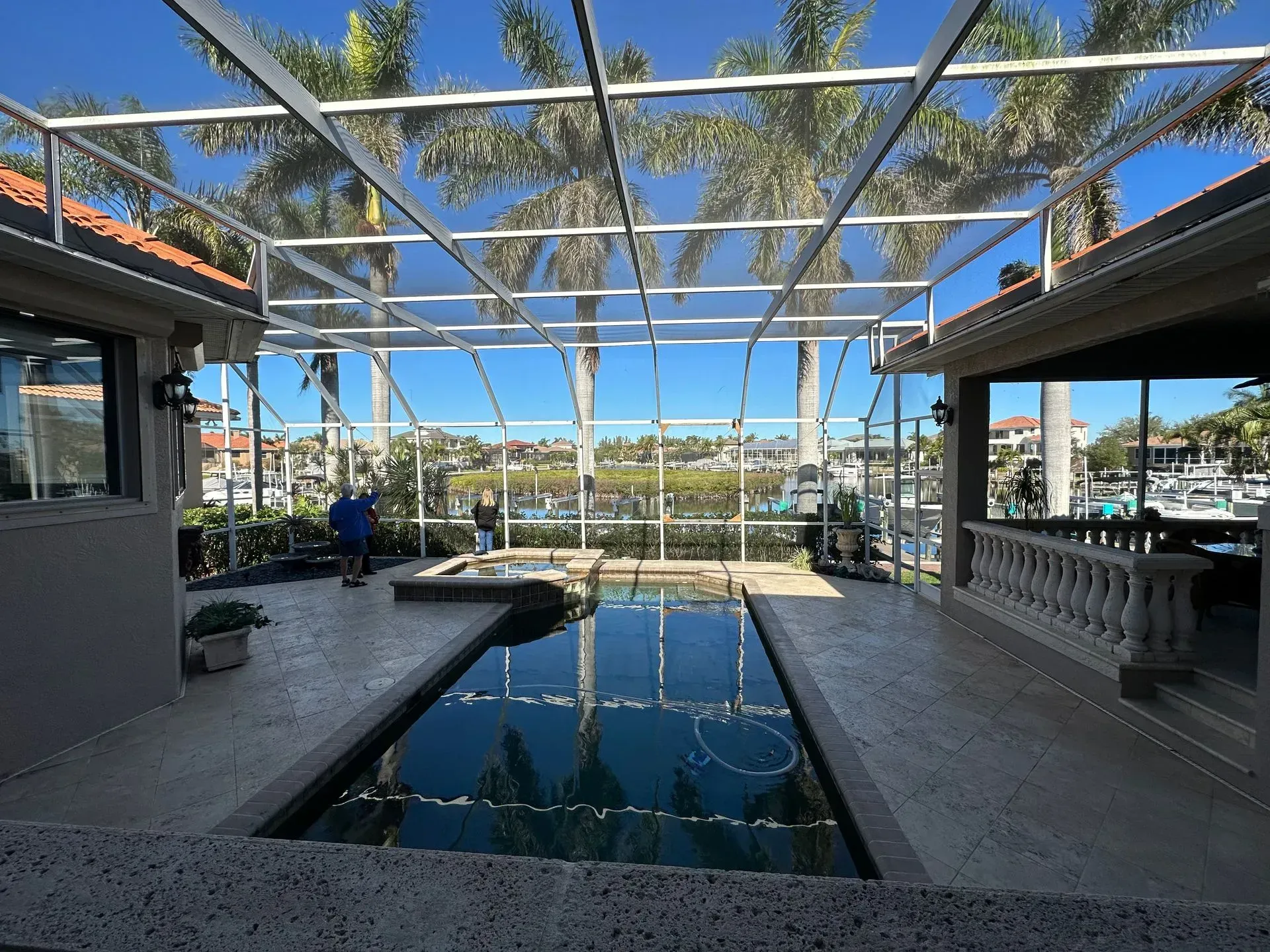 Pool patio with a pool, hot tub, and marina view, enclosed by a white screen.