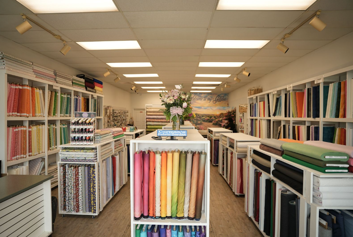 Fabric store aisle with colorful bolts of cloth and fluorescent ceiling lights