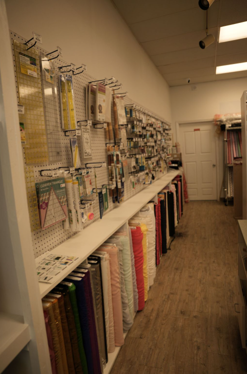 Fabric and craft supplies displayed on shelves in a narrow store aisle