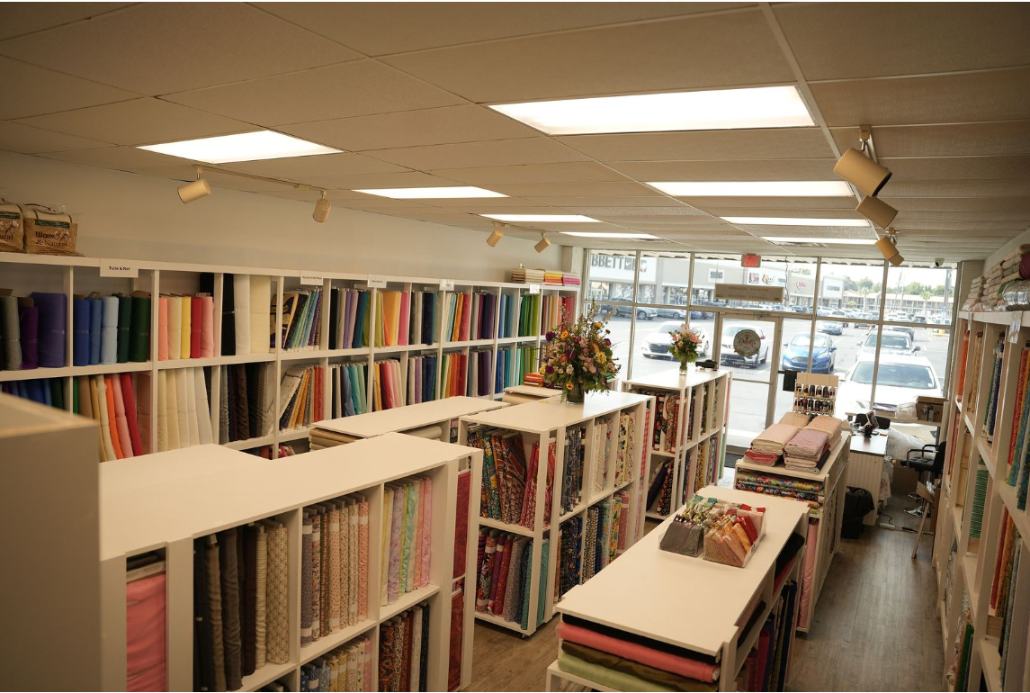 Fabric store aisle with colorful bolts of cloth and bright ceiling lights