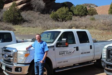 A man in a blue shirt is standing in front of a ford truck