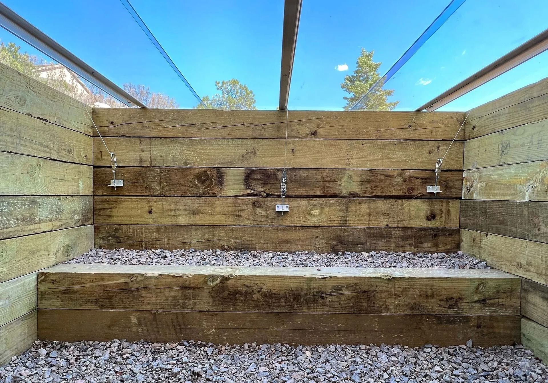 A wooden shower with two showers hanging from the ceiling.