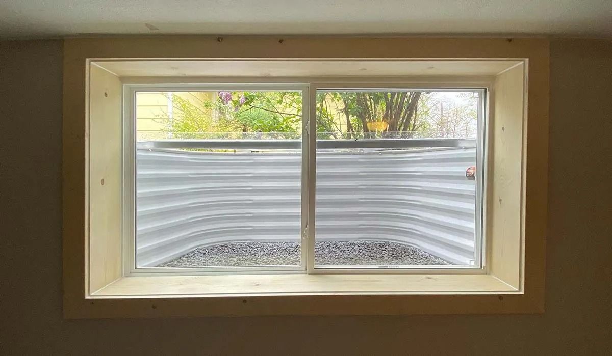 A window in the basement of a house with a cover on it.
