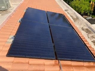 A row of solar panels are sitting on top of a tiled roof.