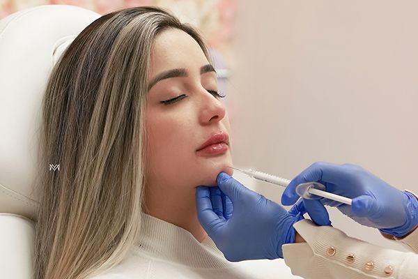 A woman is getting an injection in her chin.