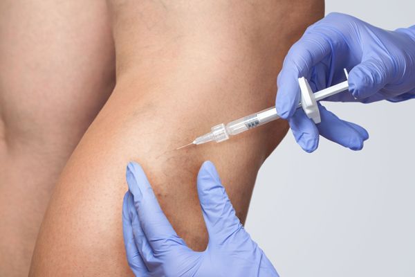 A person is getting an injection in their leg with a syringe.