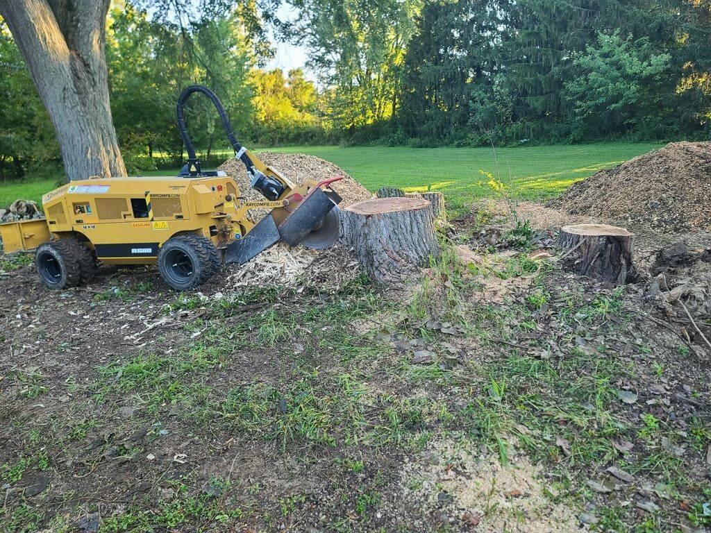 a stump grinder is sitting next to a tree stump in a field
