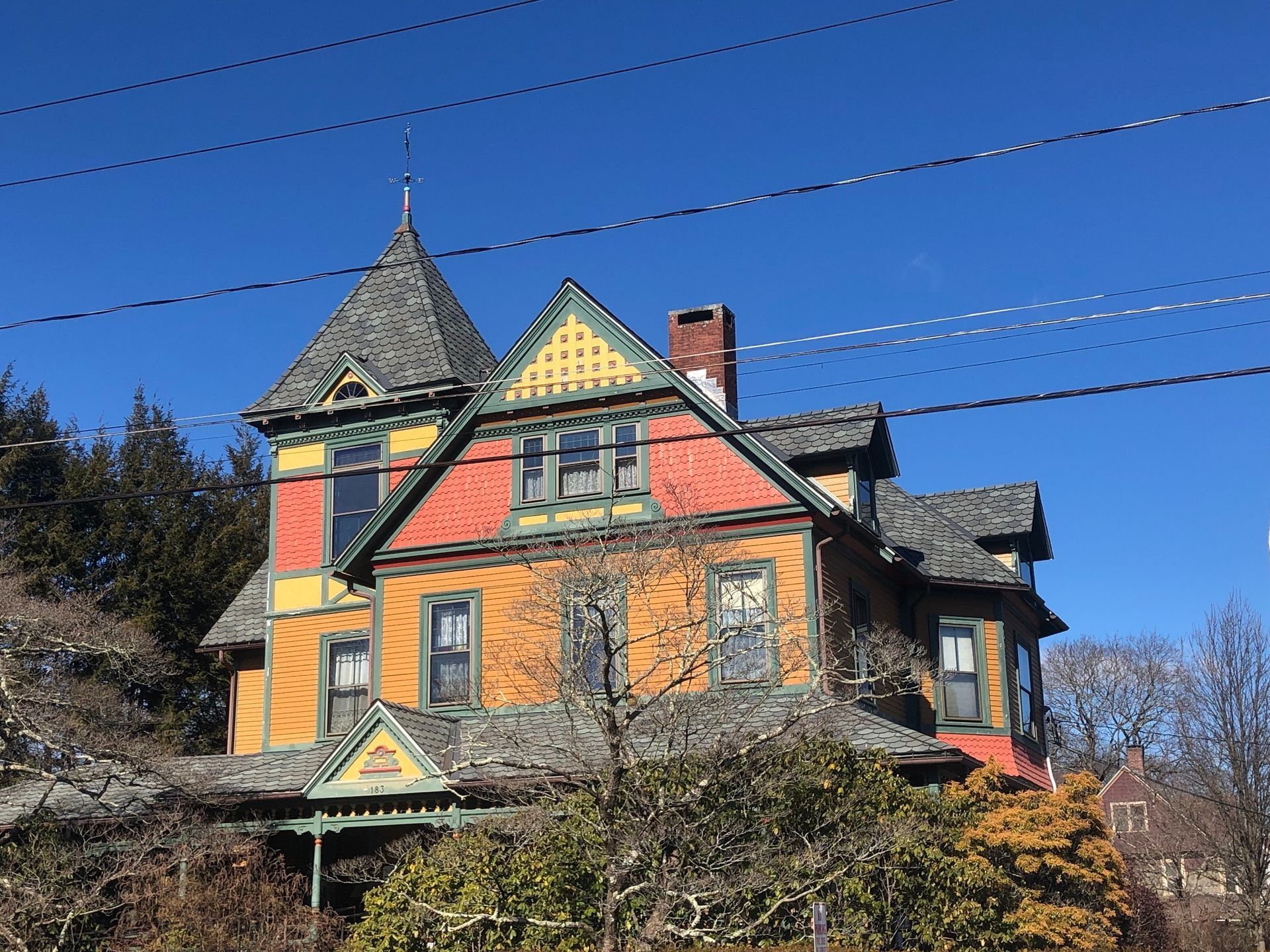 Colorful Victorian house with a tower, set against a bright blue sky.