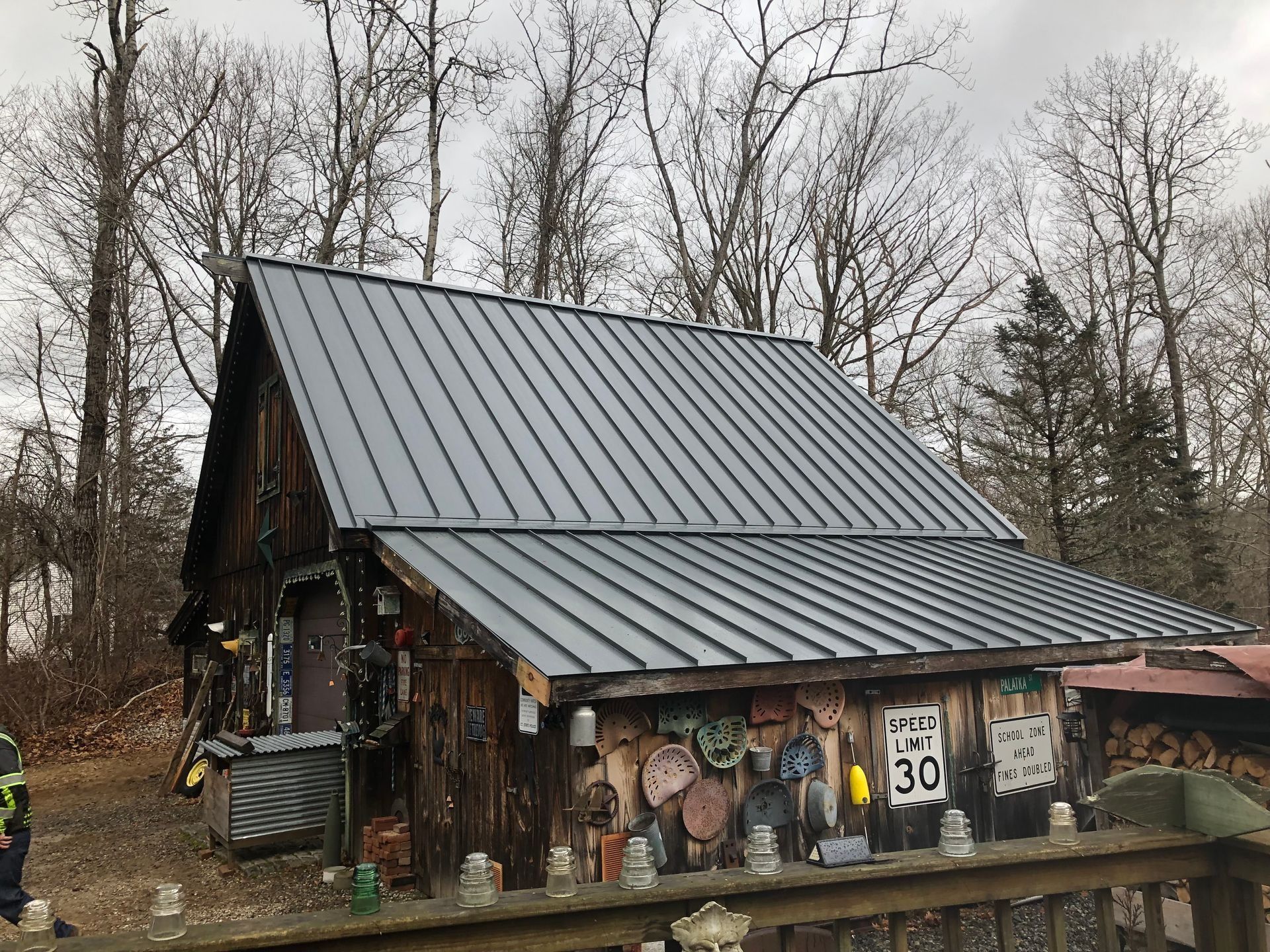 Rustic wooden building with metal roof; trees in background. Decorations on the front; gray and brown.
