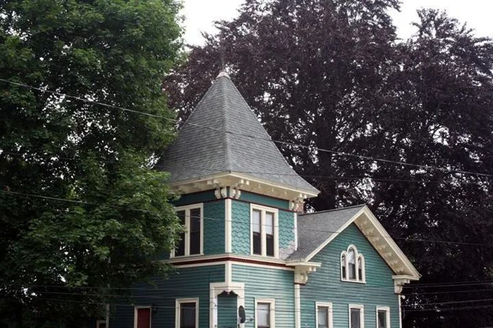 Teal Victorian house with turret, white trim, and a dark roof.