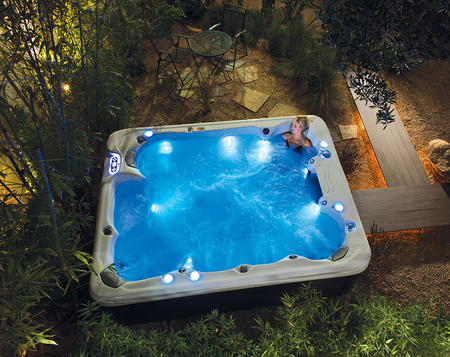 A man is sitting in a hot tub that is lit up at night