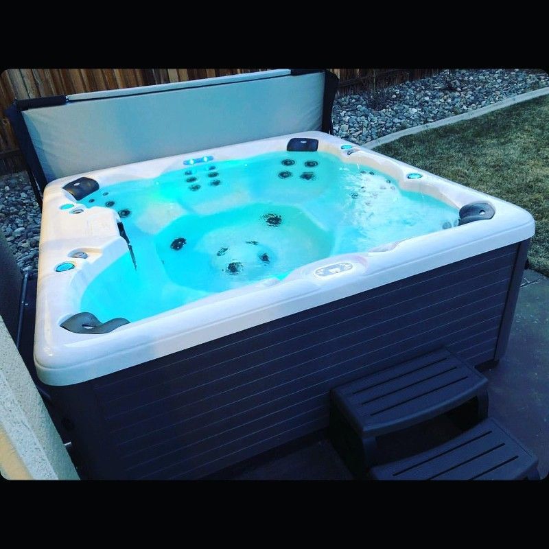 A hot tub with blue water is sitting on a sidewalk
