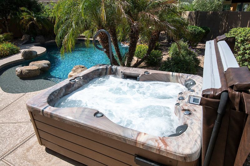 A hot tub is sitting on a patio next to a pool.