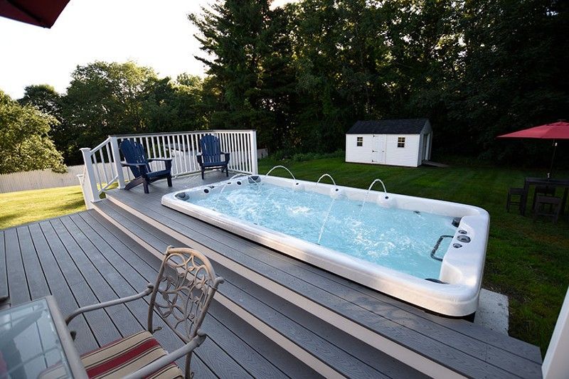 A large swimming pool is sitting on top of a wooden deck.