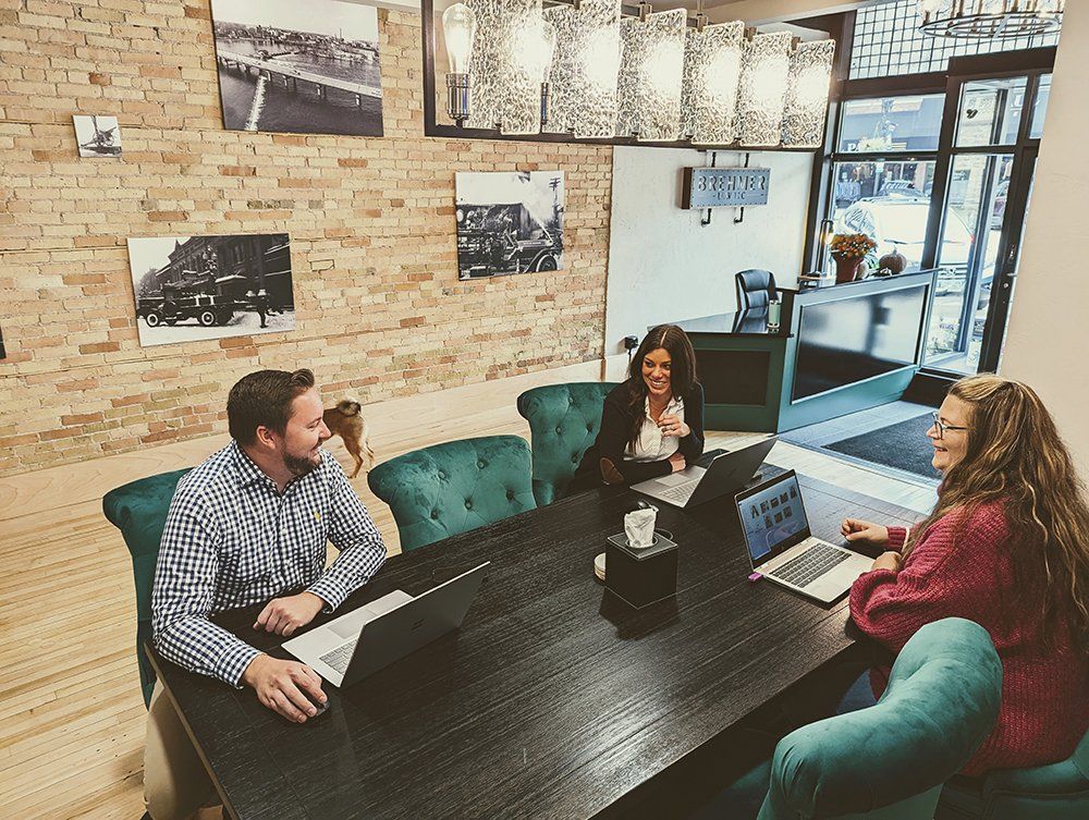A group of people are sitting around a table with laptops.