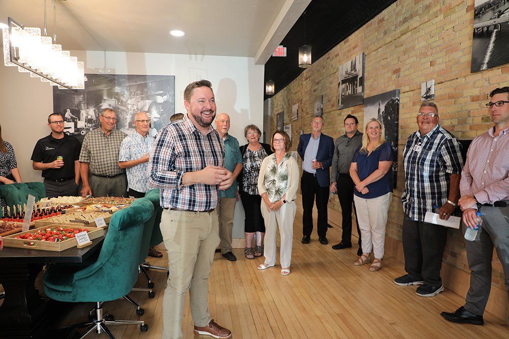 A man is standing in front of a group of people in a room.