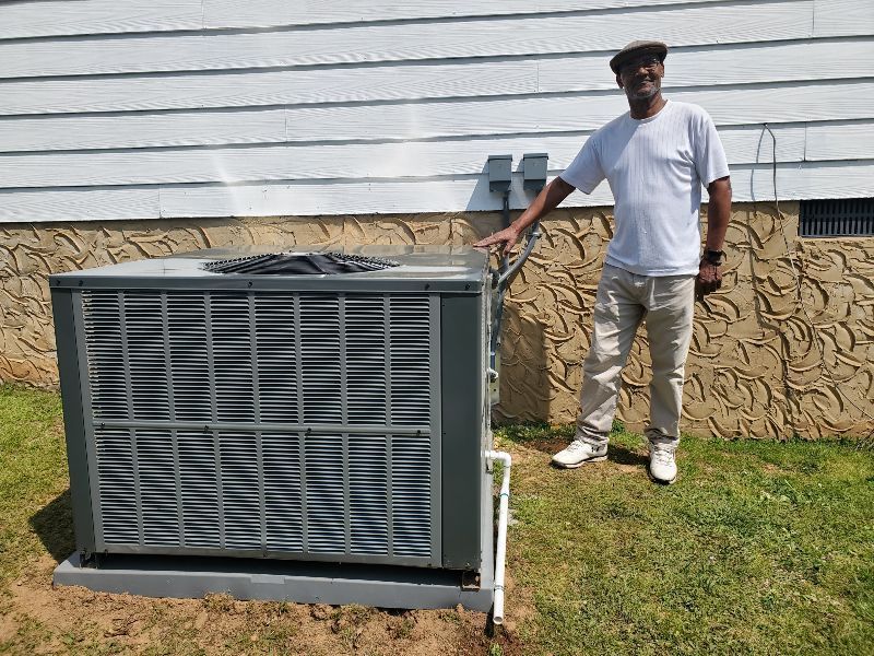 Man standing beside a large outdoor HVAC unit on a grassy lawn