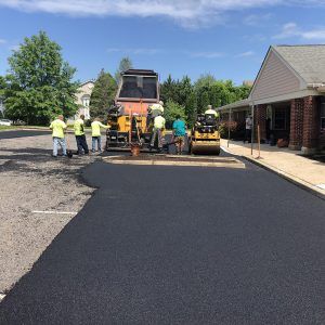 Road paving crew laying fresh black asphalt on a suburban street