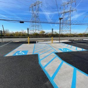 Accessible parking spaces with blue markings in a lot, under power lines and a clear sky.
