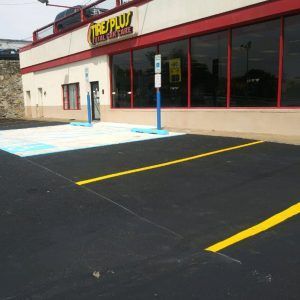 Storefront with large windows, blue accessible entrance, and marked parking spaces in front