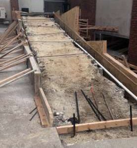 Concrete ramp under construction with wooden formwork and rebar along the sides