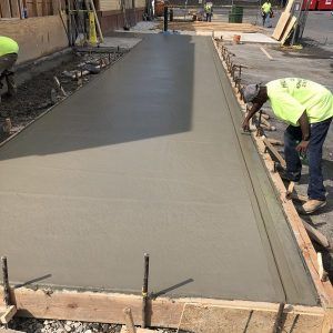 Workers smoothing wet concrete on a driveway construction site