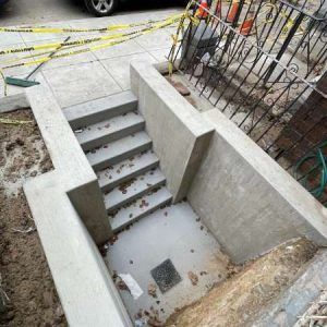 Concrete stairwell under construction with safety tape and exposed rebar around an entryway