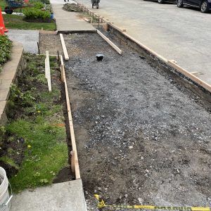Roadside gravel path under construction beside a sidewalk and parked cars